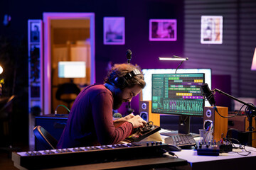 Songwriter musician mixing and mastering songs on console, using daw software interface to add...