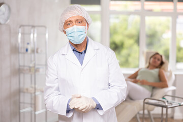 Obraz premium Smiling aged man dermatologist standing in light cosmetology cabinet with wide windows