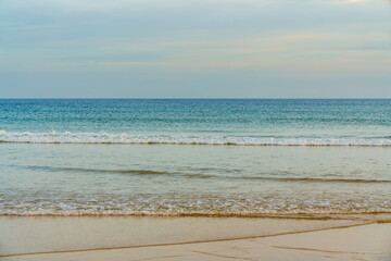 Gentle ocean waves rolling onto a sandy shore under a soft, pastel sky.