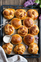 Freshly baked homemade buns arranged on a baking tray, captured from a top-down perspective.