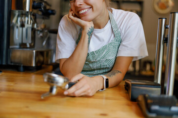 A friendly barista poses at a cozy coffee shop with a portafilter, creating a warm and inviting...