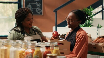 Business owner doing supply run at the local market, bringing organic freshly harvested fruits and veggies in crates. African american employee does restock with supplier, zero waste concept.