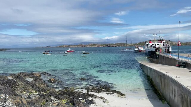 Rocky coast with clear water and boats, cloudy sky above, tour boat, holy island, Isle of Iona, Inner Hebrides, Scotland, Great Britain