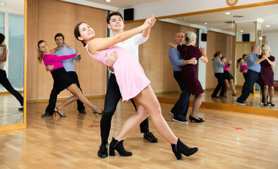 Couple of dancers rehearsing ballroom dances in dance studio
