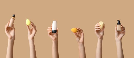 Female hands with makeup foundation and sponges on brown background