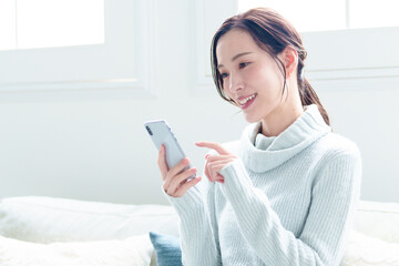 リビングでスマートフォンを使う女性