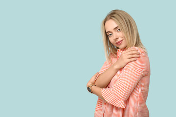 Beautiful young woman embracing herself on pink background