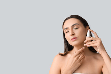 Young woman with makeup foundation on light background, closeup