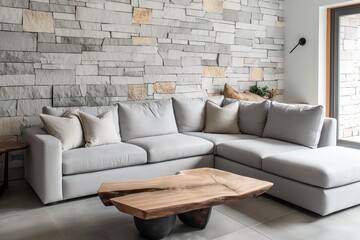 Modern living room design with gray sectional sofa and wooden coffee table. Gray stone wall with wooden panel, white tile floor and window. Minimalist home interior with cozy atmosphere.