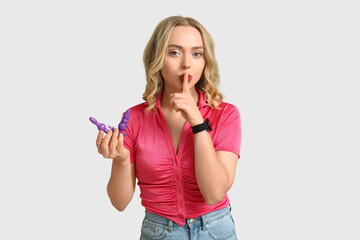 Beautiful young woman with butt plugs showing silence gesture on white background