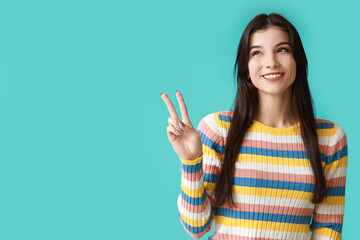 Young woman showing peace sign on blue background