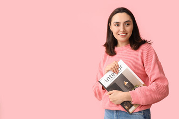 Beautiful young woman with interior magazine on pink background