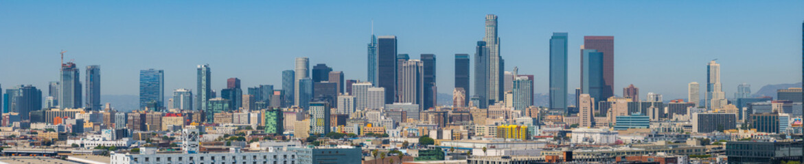 The skyline of downtown Los Angeles features skyscrapers like the U.S. Bank Tower and Wilshire Grand Center. Mountains form a scenic backdrop.