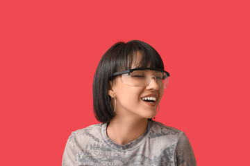 Happy stylish young woman in eyeglasses with nose piercing on red background