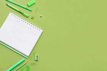 Notebook and felt-tip pens on green background. Top view