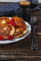 Cottage cheese pancakes with fresh raspberries on a white plate on the table