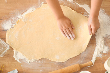 Woman preparing traditional cinnamon rolls in kitchen, top view
