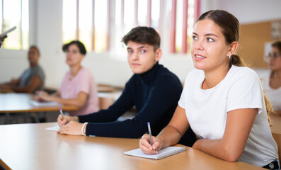 Portrait of attentive positive young female student studying on training session in lecture class