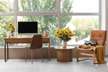 Beautiful workplace with computer and sunflowers in interior of cozy room