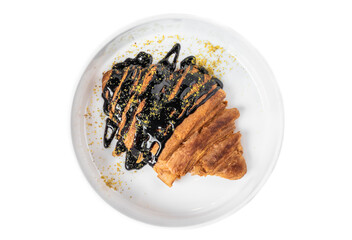 Sweet croissant with chocolate syrup in white plate on white background