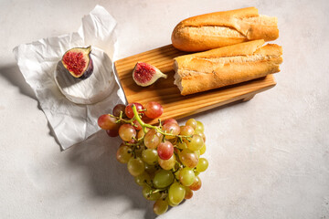 Sweet ripe grapes with fig, camembert cheese and baguette on white background