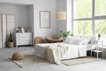 Modern interior of light bedroom with chest of drawers, bedside table and bed