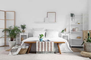 Modern interior of bedroom with bench, bed, bedside table and houseplant