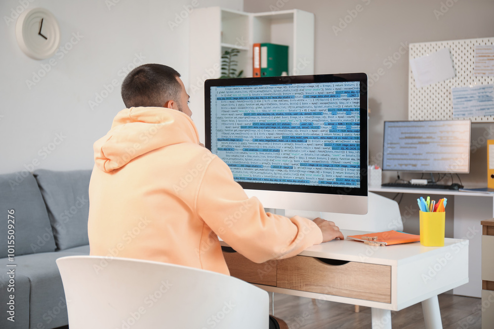 Aufkleber male programmer working with computer at desk in office, back view
