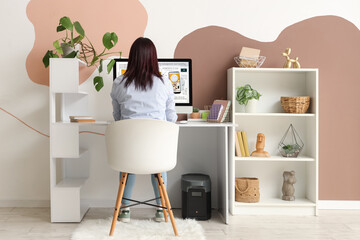 Female web designer working with computer at table in office, back view