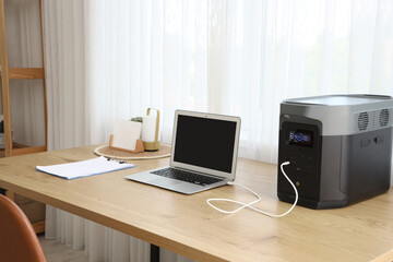 Portable power station charging laptop on table in office