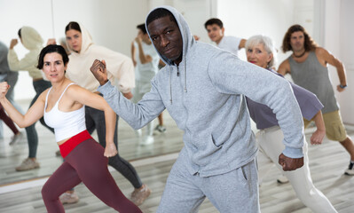Group of dancing people practice synchronized choreography in a dance studio in the lesson