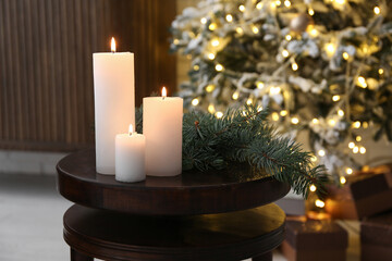 Christmas branches with burning candles on table in living room, closeup