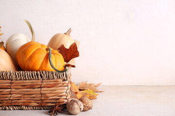 Wicker box with fresh pumpkins, star anise, walnuts and autumn leaves on white background