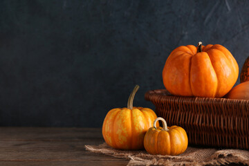 Wicker basket with fresh pumpkins on wooden table