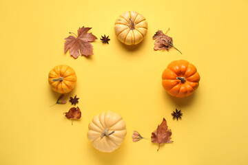 Frame made of fresh pumpkins with star anise and autumn leaves on yellow background