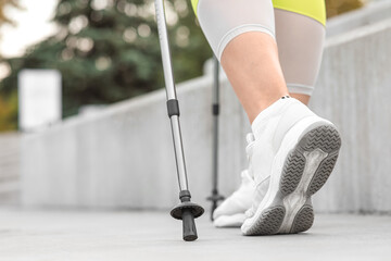 Sporty woman doing Nordic walking outdoors, closeup