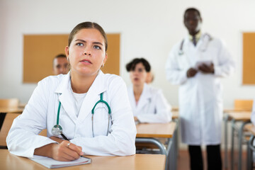 Fototapeta premium Doctors different age sitting at desk in classroom working during lesson at adult education class