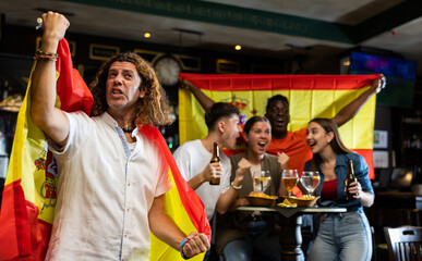 Fototapeta premium Happy fans celebrating the victory of Spanish team in the bar