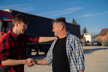 Fleet manager and driver shaking hands , or hands shake of two truckers collogues smiling and...
