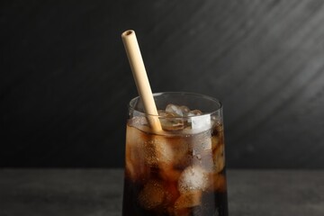 Tasty refreshing drink with straw in glass on grey table, closeup