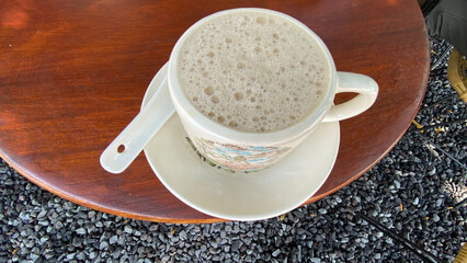 a cup of coffee sits on a table next to a plate of cups.