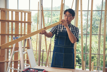 DIY craftsperson asian man working wood heap carpenter objects woodwork desk. Architect man hands...