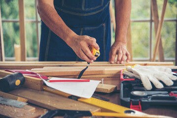 DIY craftsperson asian man working wood heap carpenter objects woodwork desk. Architect man hands use ruler measure hammer home improvement. Wooden builder carpenter repairing construction workshop