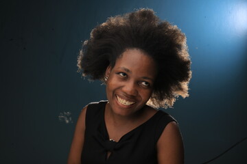 Headhoot of an African American Lady in a black dress smiling and she is more than pretty with natural black hair