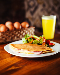 Crepas saladas con jamón, queso con una deliciosa ensalada, una cesta con huevos y un jugo natural refrescante