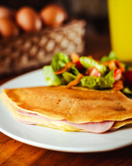 Crepas saladas con jamón, queso con una deliciosa ensalada, una cesta con huevos y un jugo natural refrescante