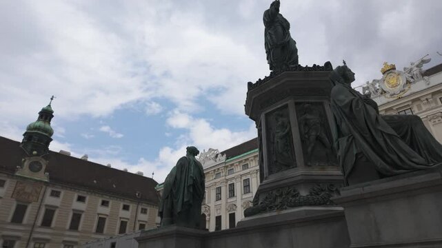 Statue in Vienna's Innerer Burghof, surrounded by historic palace buildings and clock tower, Austria