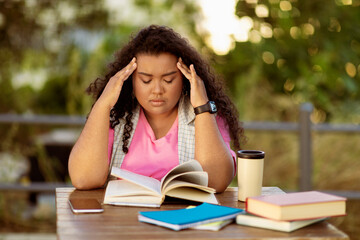 A student sits at a table in a serene outdoor environment, looking stressed as she attempts to study