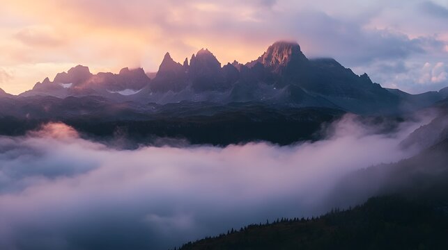 A mountain landscape with clouds rolling over the peaks at sunrise