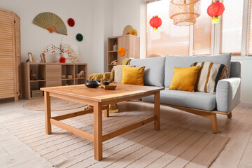 Interior of festive living room with tea set on table, grey sofa and traditional Chinese...
